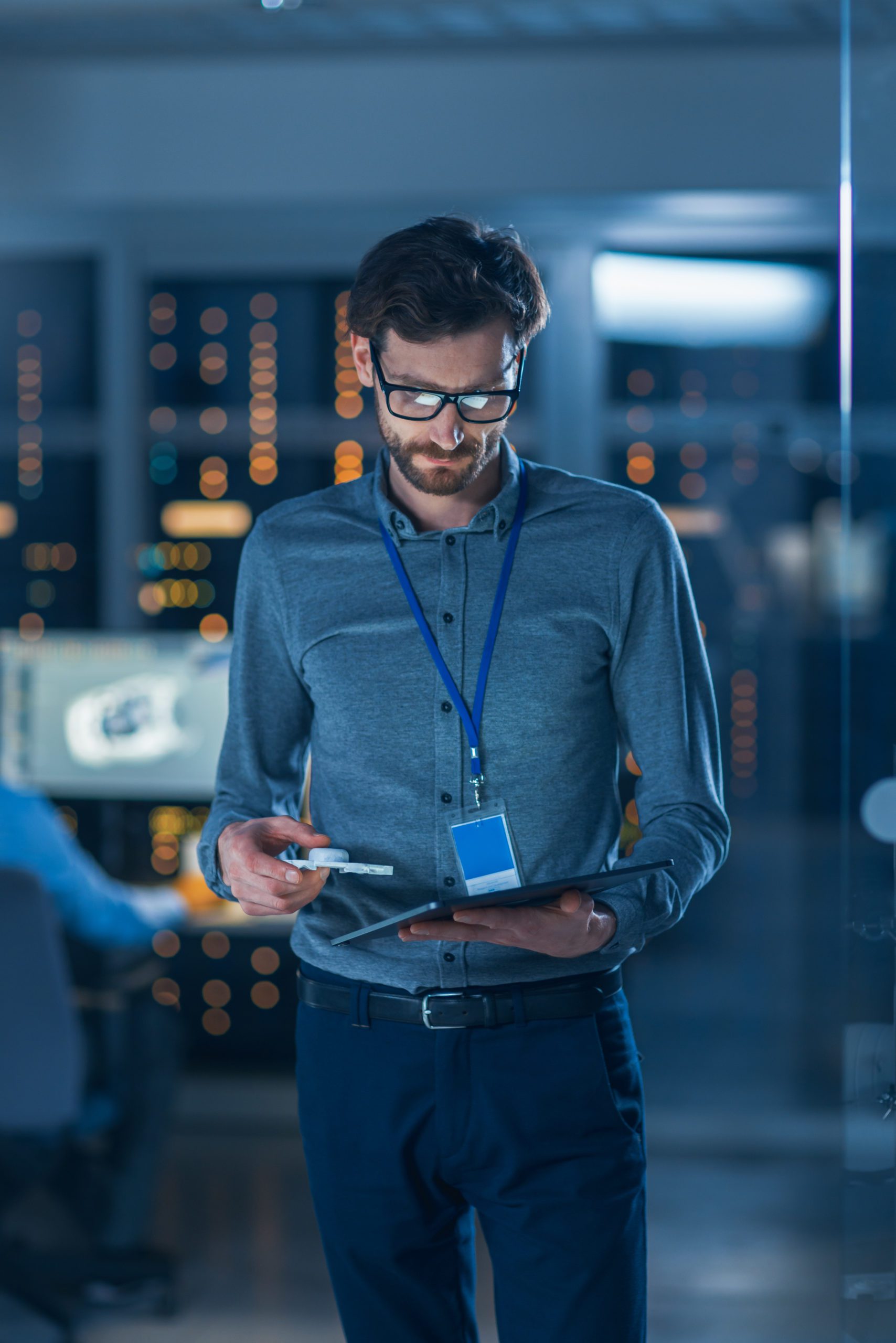In Technology Research Facility: Chief Engineer Stands in the Middle of the Lab and Uses Tablet Computer. Team of Industrial Engineers, Developers Work on Engine Design Use Digital Whiteboard and Computers Young Software Engineer